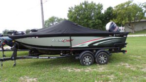 Covered fishing boat on trailer on grass