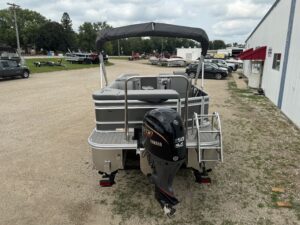 Pontoon boat with motor parked outside building.