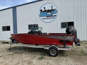 Red G3 boat displayed outside a marine shop.