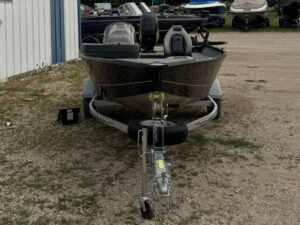 Black fishing boat on trailer outdoors.