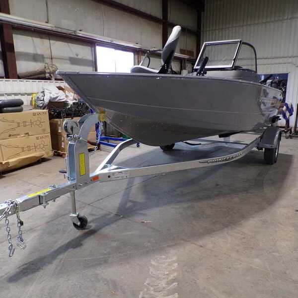 A boat is parked in the warehouse with its trailer.